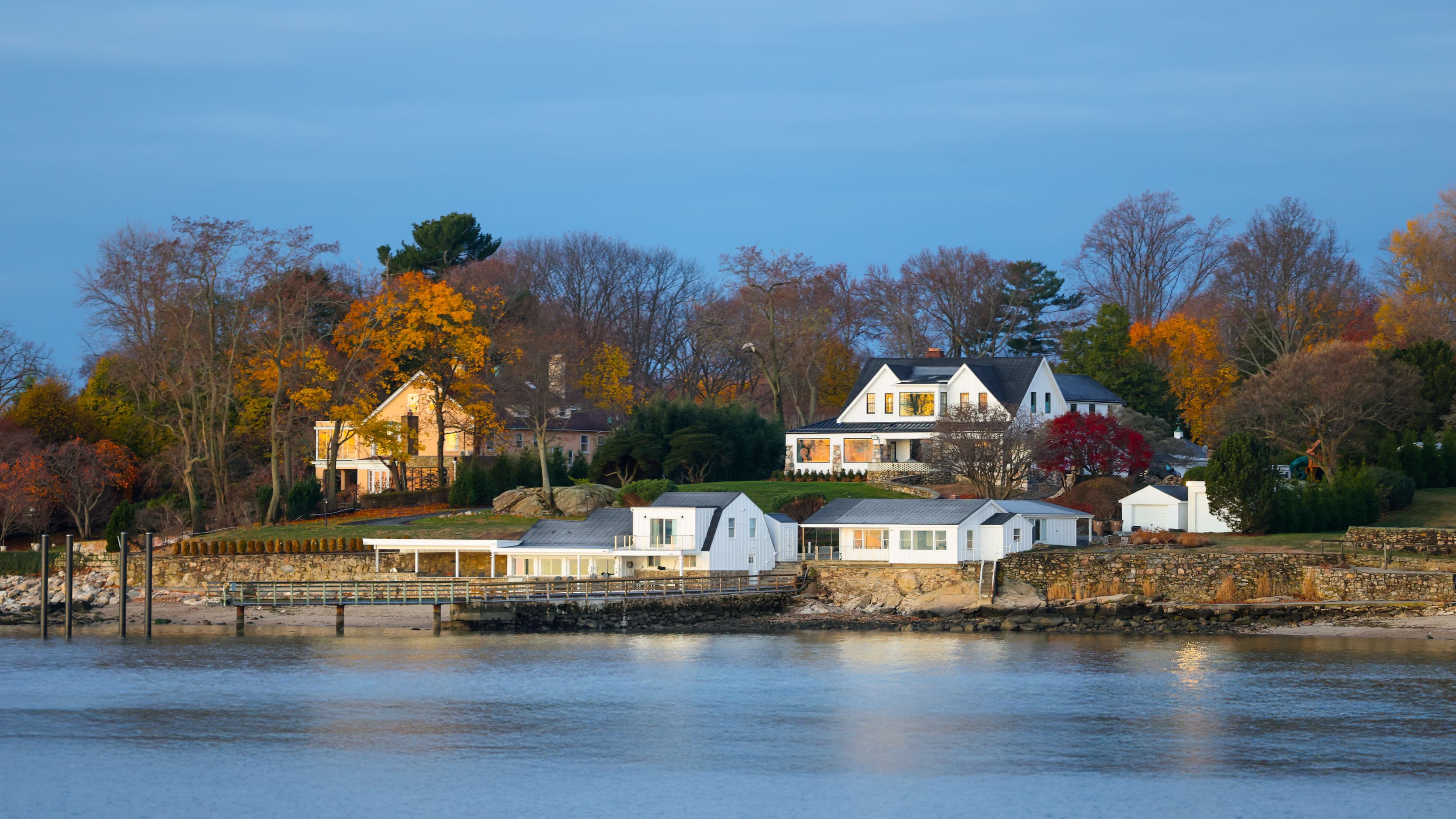 White houses on the water in Fairfield County, Connecticut, among autumn trees at sunrise